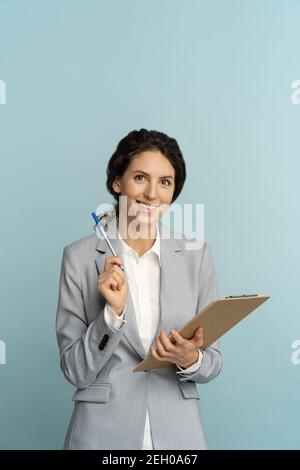 Amichevole agente di assicurazione donna indossare blazer grigio tenendo appunti, penna guardando fotocamera, isolato. Foto Stock