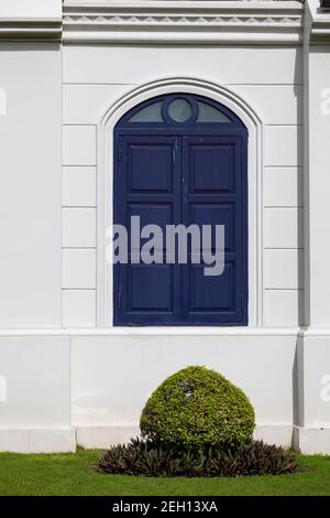 Una finestra blu si staglia contro una parete bianca all'interno del Grand Palace di Bangkok, Thailandia Foto Stock