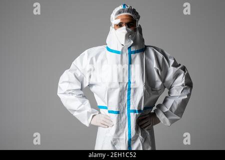 Ritratto di medico uomo che indossa googles, occhiali protettivi in tuta di protezione, maschera chirurgica viso su sfondo bianco. Foto Stock