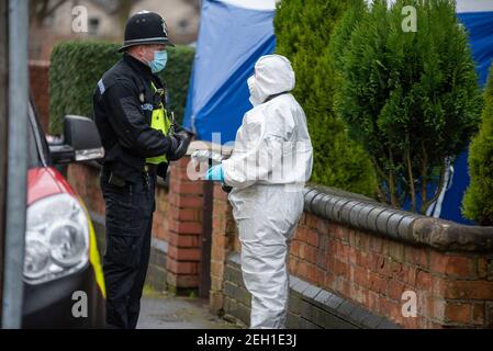 Handsworth, Birmingham, West Midlands, Regno Unito. 19 febbraio 2021: L'ufficiale forense parla con un ufficiale di polizia sulla scena. Un uomo è morto dopo una beatola in una proprietà su Church Hill Road intorno alle 5:20 venerdì mattina. Gli ufficiali di Forensics hanno combattuto la casa e una tenda blu rimane fuori della proprietà. Credit: Ryan Underwood / Alamy Live News. Foto Stock