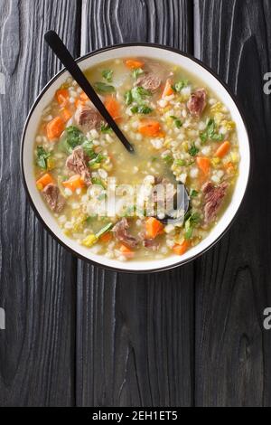 Tradizionalmente Scotch Broth è fatto con agnello cotto con le verdure, orzo, e piselli secchi in primo piano nel piatto sulla tavola. Vista dall'alto verticale f Foto Stock