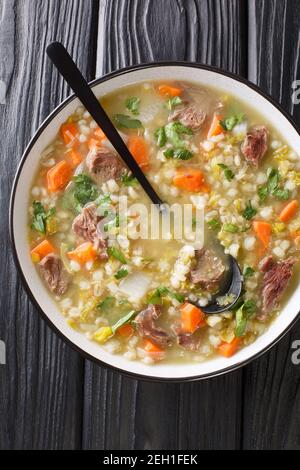 Il brodo Scotch è una tradizionale zuppa scozzese a base di agnello e verdure, orzo, piselli nel piatto sul tavolo. Vista dall'alto verticale da abo Foto Stock