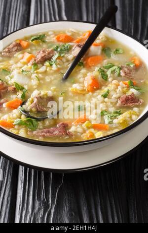 Tradizionalmente Scotch Broth è fatto con agnello cotto con le verdure, orzo, e piselli secchi in primo piano nel piatto sulla tavola. Verticale Foto Stock