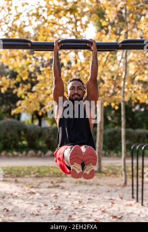 il ragazzo afro americano dell'atleta fa gli esercizi di idoneità di calisthenics sui bar nel parco Foto Stock