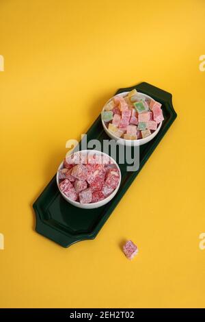 due ciotole di rahat lakoum su un vassoio isolato su fondo giallo piatto posare. Dolce concetto turco. L'immagine contiene spazio per la copia Foto Stock