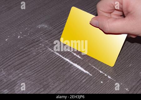 Mano femminile che tiene una carta di credito e distribuisce farmaci su un tavolo scuro Foto Stock