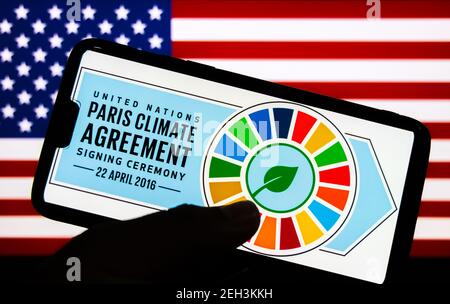 Kathmandu, Nepal - Febbraio 19 2021: Logo dell'accordo sul clima di Parigi contro la bandiera degli Stati Uniti d'America. Gli Stati Uniti sono ufficialmente rientrati a Parigi Climat Foto Stock