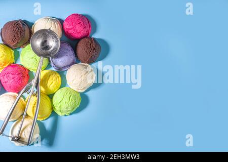Coloratissimi cucchiai di gelato su sfondo blu pastello. Summer minimalism motivo piatto con luce dura. Mirtillo alla vaniglia al cioccolato Foto Stock
