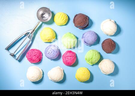 Coloratissimi cucchiai di gelato su sfondo blu pastello. Summer minimalism motivo piatto con luce dura. Mirtillo alla vaniglia al cioccolato Foto Stock