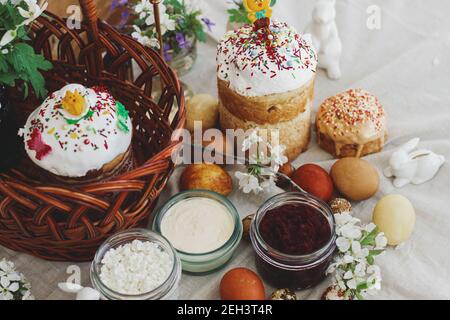 Cibo pasquale tradizionale per la benedizione, pane pasquale fatto in casa, uova di pasqua eleganti e fiori di primavera fioritura su tovagliolo di lino su tavola rustica. Felice EA Foto Stock