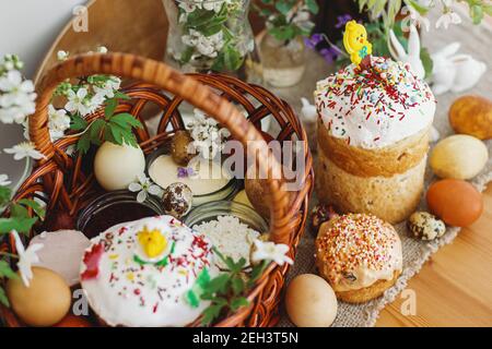 Cibo pasquale tradizionale per la benedizione, pane pasquale fatto in casa, uova di pasqua eleganti e fiori di primavera fioritura su tovagliolo di lino su tavola rustica. Felice EA Foto Stock