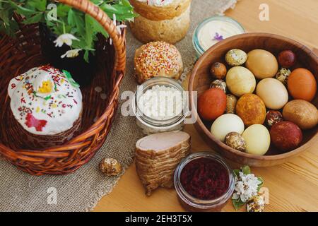 Cibo pasquale tradizionale per la benedizione, pane pasquale fatto in casa, uova di pasqua eleganti e fiori di primavera fioritura su tovagliolo di lino su tavola rustica. Felice EA Foto Stock