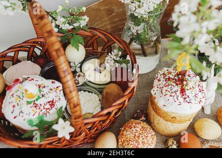 Cibo pasquale tradizionale per la benedizione, pane pasquale fatto in casa, uova di pasqua eleganti e fiori di primavera fioritura su tovagliolo di lino su tavola rustica. Felice EA Foto Stock