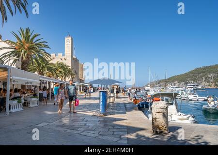 Komiza, Croazia - 16 agosto 2020: I turisti camminano sul porto della città vecchia nel pomeriggio soleggiato Foto Stock