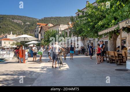 Komiza, Croazia - 16 agosto 2020: I turisti camminano sul porto della città vecchia nel pomeriggio soleggiato Foto Stock