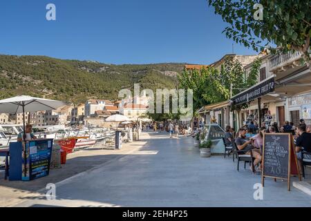 Komiza, Croazia - 16 agosto 2020: I turisti camminano sul porto della città vecchia nel pomeriggio soleggiato Foto Stock