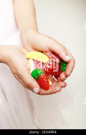 ragazza che tiene la caramella colorata nelle sue mani Foto Stock