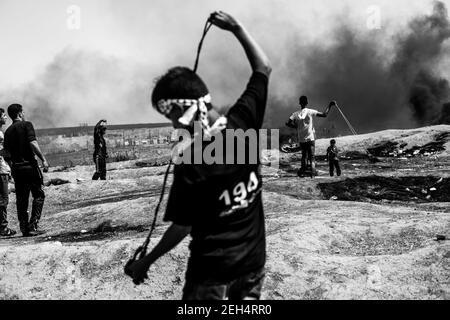 Un dimostratore palestinese usa un colpo di schiaffo per gettare pietre contro le forze israeliane durante le manifestazioni sul confine orientale della città di Gaza con Israele. Le tensioni sono elevate lungo il confine tra Gaza e Israele dopo più di un mese di proteste di massa settimanali vicino alla barriera che ha ucciso 50 dimostranti palestinesi e ferito oltre 1,700 persone da un incendio militare israeliano. I leader di Hamas a Gaza hanno promesso che le marce continueranno fino alla revoca del blocco decennale israeliano del territorio. Le proteste sono previste anche il 14 e 15 maggio, il giorno in cui i palestinesi segneranno Yawm An-Nakba o 'giorno di disgusto Foto Stock