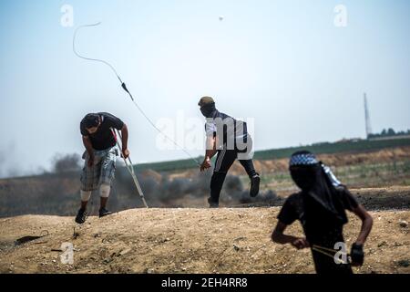 Un dimostratore palestinese usa un colpo di schiaffo per gettare pietre contro le forze israeliane durante le manifestazioni sul confine orientale della città di Gaza con Israele. Le tensioni sono elevate lungo il confine tra Gaza e Israele dopo più di un mese di proteste di massa settimanali vicino alla barriera che ha ucciso 50 dimostranti palestinesi e ferito oltre 1,700 persone da un incendio militare israeliano. I leader di Hamas a Gaza hanno promesso che le marce continueranno fino alla revoca del blocco decennale israeliano del territorio. Le proteste sono previste anche il 14 e 15 maggio, il giorno in cui i palestinesi segneranno Yawm An-Nakba o 'giorno di disgusto Foto Stock