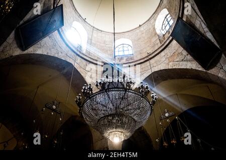 Un lampadario illuminato da un raggio di luce pende dal soffitto di una delle sale del Santo Sepolcro. Il Santo Sepolcro è, secondo la tradizione cristiana, la tomba di Cristo, cioè il sepolcro dove si dice che il corpo di Gesù di Nazaret sia stato deposto la sera della sua morte sulla Croce. 9 maggio 2018. Gerusalemme. Israele Foto Stock