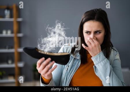 Donna che odora le scarpe Stinky. Piedi Sweat e Odor Foto Stock
