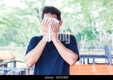 Uomo che strofina il sudore sul viso a causa del tempo caldo nei parchi Foto Stock