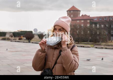 La donna rimuove la maschera medica protettiva dal viso. Il turista toglie la maschera all'aperto. Foto Stock