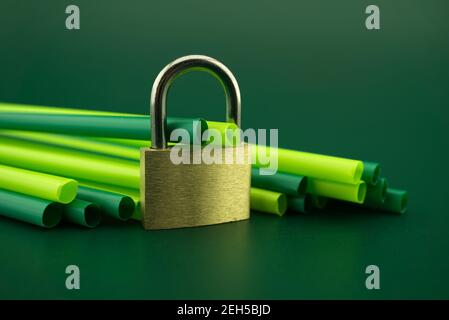 Pachlock e cannucce di plastica per bevande su sfondo verde. Divieto di utilizzare il concetto di cannucce da bere in plastica Foto Stock