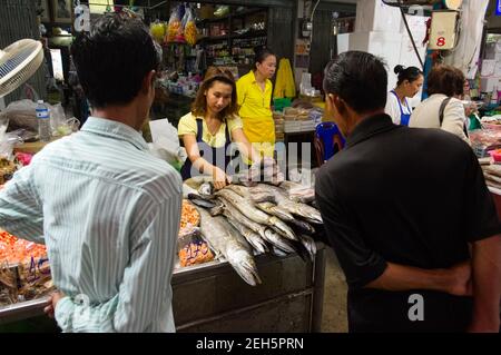 Samut Songkhram, Thailandia - Giugno, 2015: Due uomini che scelgono il pesce crudo. Giovane ragazza che vende frutti di mare sul mercato di strada a Mae Klong. Foto Stock