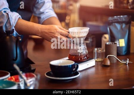 Barista che misura il gocciolamento del caffè con tazza di vetro Foto Stock