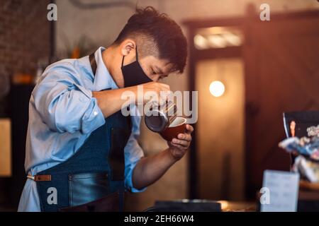 barista che prepara il cappuccino. Versare il latte per preparare una tazza di caffè. Latte art Foto Stock