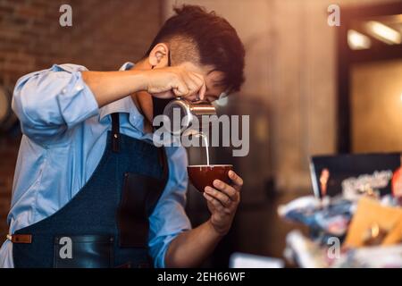 barista che prepara il cappuccino. Versare il latte per preparare una tazza di caffè. Latte art Foto Stock