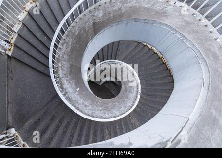 Vecchia scala a chiocciola in cemento all'aperto con ringhiere in metallo arrugginito Foto Stock