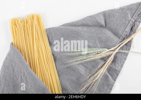 Spaghetti non cotti su tovaglia grigia con grano Foto Stock