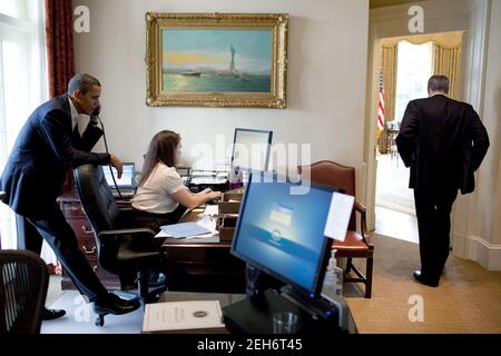 Il presidente Barack Obama parla al telefono con un membro del Congresso, mentre Katie Johnson, il segretario personale del presidente, lavora alla sua scrivania nell'Outer Oval Office, 21 marzo 2010. Phil Schiliro, assistente del Presidente degli Affari legislativi, si trova nelle vicinanze. Foto Stock