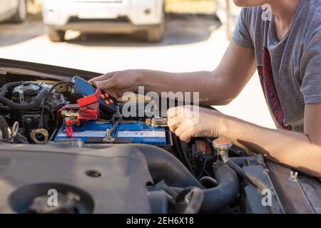 Riparazione e ispezione della batteria dell'auto. L'operatore misura la tensione e la capacità della batteria con un tester. Servizio auto. Foto Stock