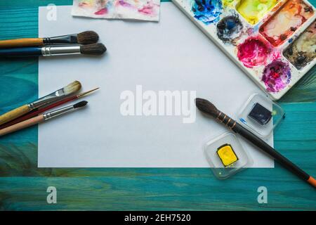vista dall'alto sulla varietà di vernici ad acquerello che creano materiali di consumo come pennelli, vernici, carta e palette Foto Stock