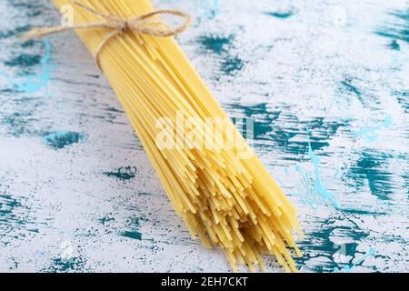 Spaghetti non cotti legati con corda su una superficie colorata Foto Stock