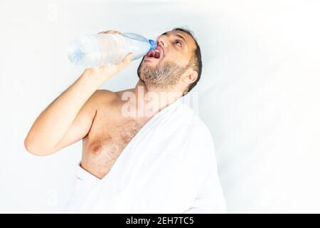 Uomo musulmano che beve dell'acqua dopo la conclusione di haj Foto Stock