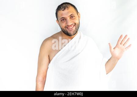 Uomo musulmano che agita con la mano mentre indossa abiti umrah Foto Stock