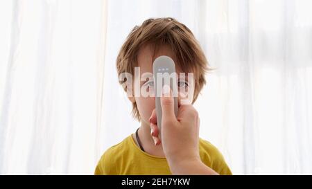 Cute bambino ha la temperatura misurata con termometro elettronico su bianco sfondo Foto Stock