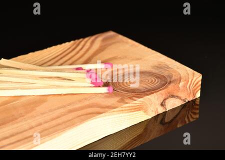 Diversi incontri di legno giacciono su una tavola di legno su uno sfondo nero. Foto Stock