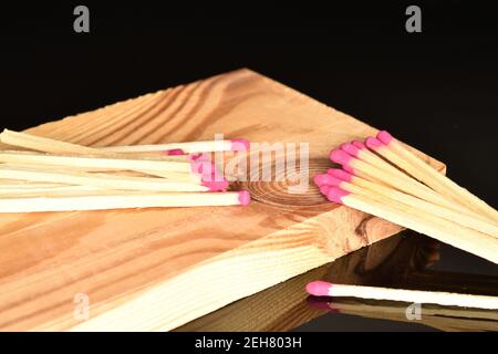 Diversi incontri di legno giacciono su una tavola di legno su uno sfondo nero. Foto Stock