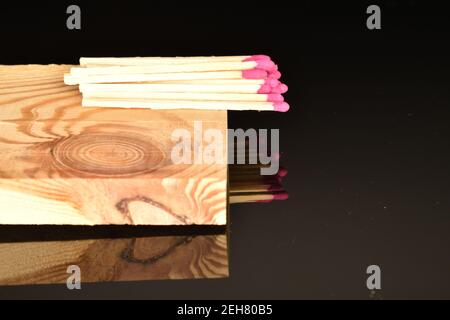 Diversi incontri di legno giacciono su una tavola di legno su uno sfondo nero. Foto Stock