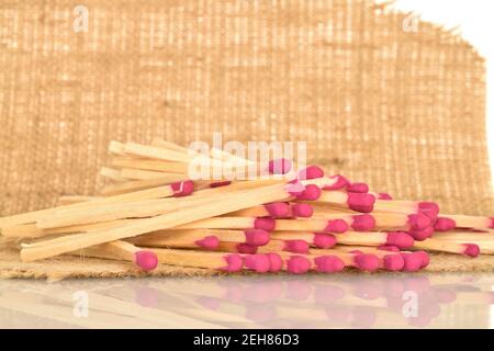 Diversi fiammiferi di legno giacciono su tessuto di iuta, su uno sfondo bianco. Foto Stock