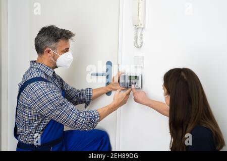 Installazione del sistema di allarme antifurto da parte del tecnico in maschera facciale Foto Stock