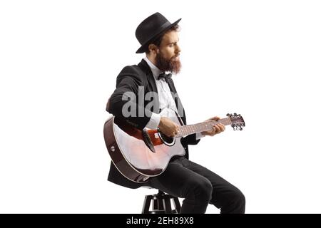 Uomo bearded seduto su una sedia e che suona un acustico chitarra isolata su sfondo bianco Foto Stock