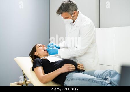 Incinta Donna decadimento dente. Controllo di odontoiatria da dentista in maschera facciale Foto Stock