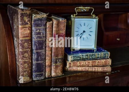 libri antichi sulla scrivania e orologio Foto Stock