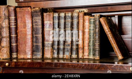 libri vecchi posti su mensola di legno Foto Stock
